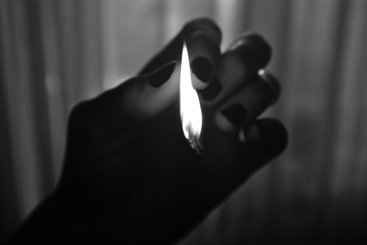 CLOSE-UP OF HAND HOLDING BURNING CANDLES