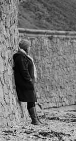 Side view full length of woman standing by wall