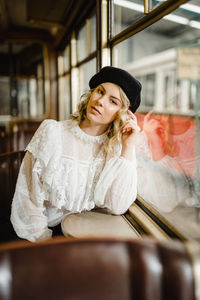 Young lady with blonde curly hair and with black beret sitting in historical tram. 