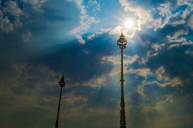 sky, low angle view, cloud - sky, street light, cloudy, lighting equipment, cloud, sunbeam, sun, sunlight, tall - high, silhouette, blue, outdoors, nature, no people, communications tower, lens flare, day, weather