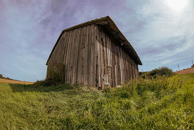 Old barn on field against sky