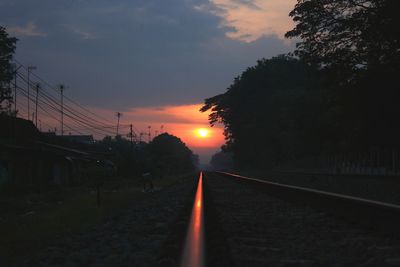 Surface level of railroad tracks against sky during sunset