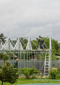 Manual workers making metallic built structure on field