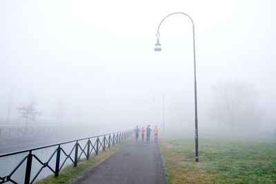 Rear view of people on street against sky during winter