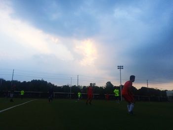 People playing soccer on field against sky