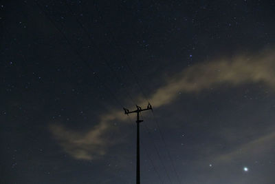 Low angle view of silhouette electricity pylon against sky at night