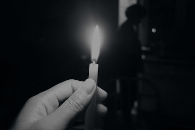 Close-up of hand holding burning candle