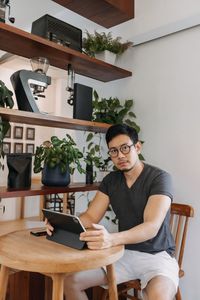 Young woman using mobile phone while sitting on chair at home