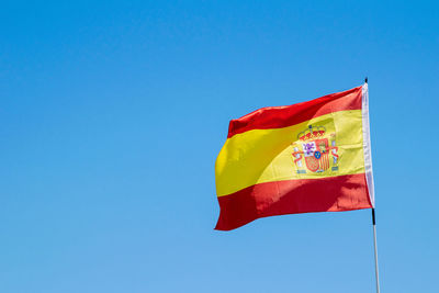 Low angle view of flag against blue sky
