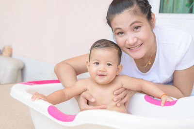 Portrait of mother with daughter in bathtub at home