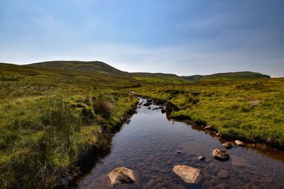 Scenic view of stream amidst rocks against sky