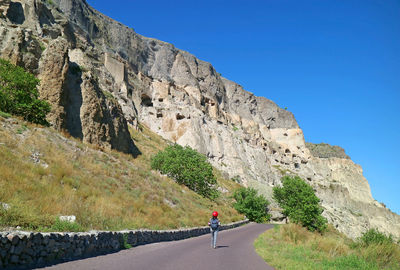 Visitor on the trail climbing onto vardzia, medieval cave city dug out of the mountain in georgia