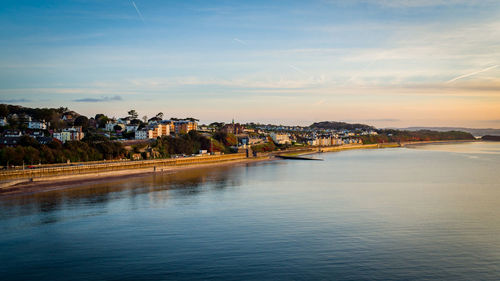 View of townscape by sea against sky during sunset