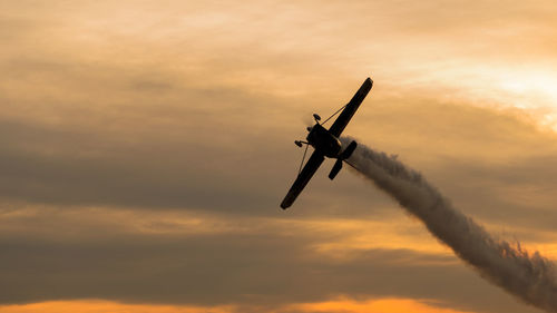 Low angle view of silhouette airplane flying against sky during sunset