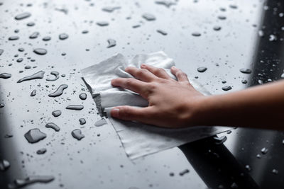 Close-up of hand touching wet glass during rainy season