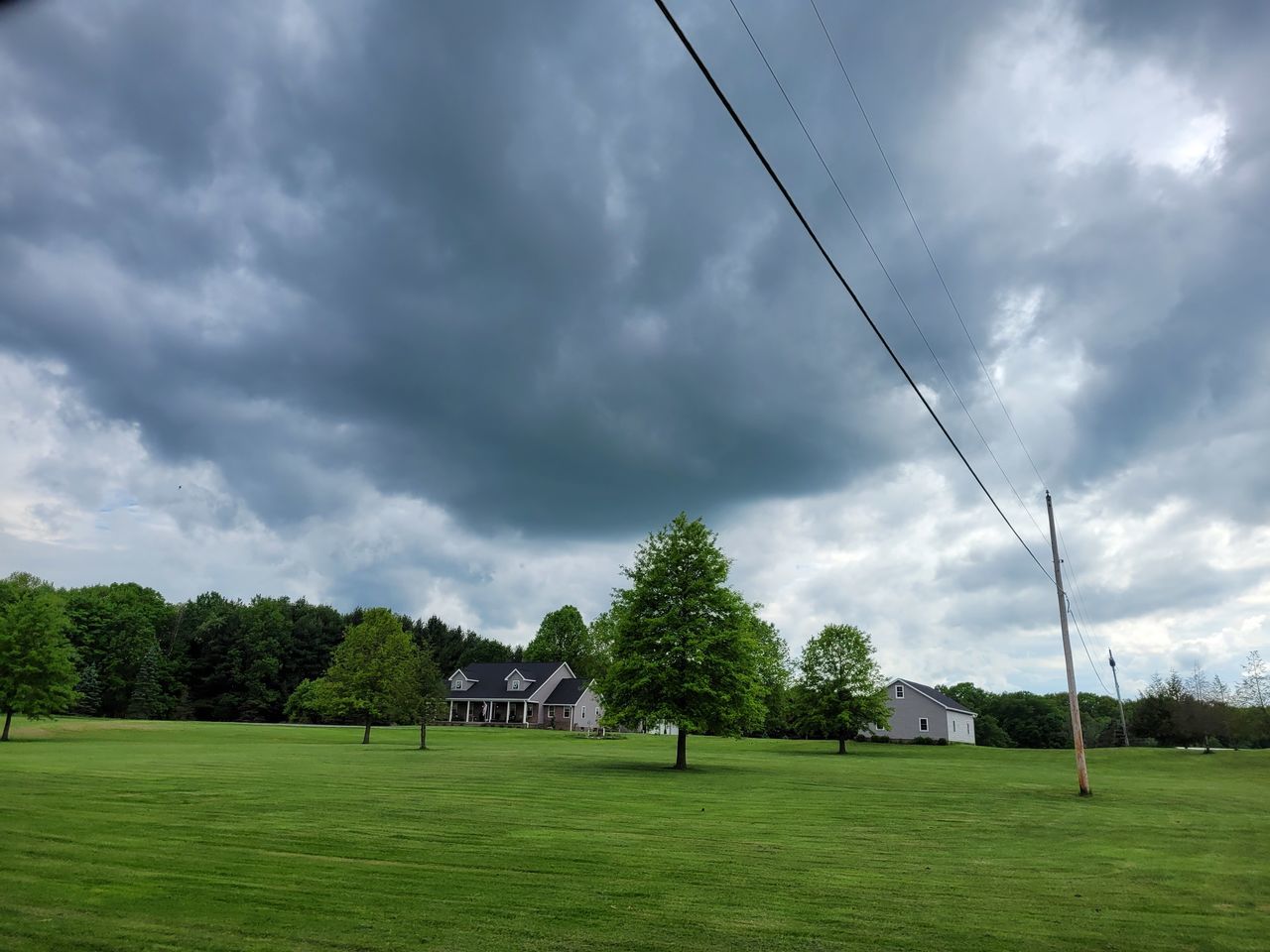 cloud, sky, grass, plant, tree, nature, green, environment, lawn, field, sports, sport venue, landscape, beauty in nature, storm, overcast, rural area, no people, land, architecture, grassland, scenics - nature, dramatic sky, cloudscape, plain, outdoors, golf club, built structure, storm cloud, meadow, day, tranquility, cable, sunlight, tranquil scene, golf, electricity, building, non-urban scene, activity