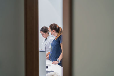 Side view of medical practitioners browsing data on modern computer while working in lab of modern hospital together