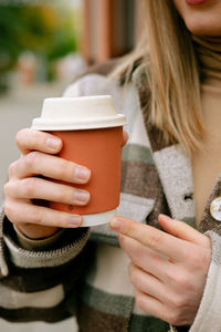 Midsection of woman holding coffee cup