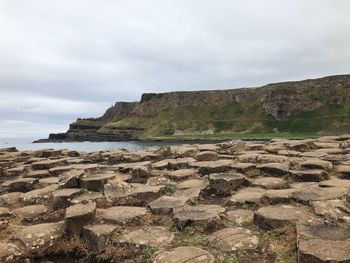 Scenic view of rocks by sea against sky