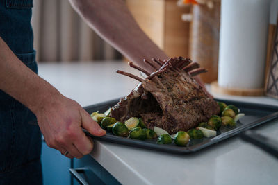 Roasted rack of lamb on a tray in the hands of the chef. barbecue season