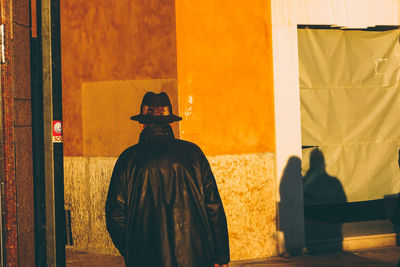 Rear view of man standing against yellow wall