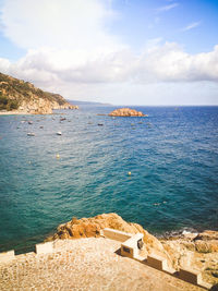 View of calm beach against cloudy sky