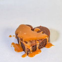 Heart shaped chocolate cake dripping with delicious caramel sauce, square photo