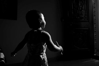 Rear view of girl standing in darkroom