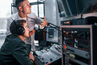 Conception of teamwork. two guys is indoors in the radio studio is busy by broadcast.