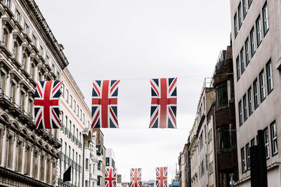 Union jack flags hanging between rows of buildings in london.