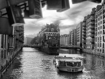 Canal amidst buildings in city against sky