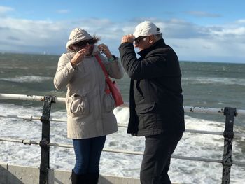 Senior couple standing by sea against sky