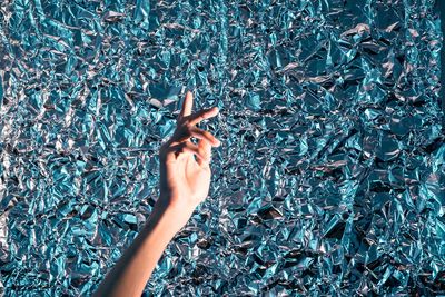 Cropped image of woman hand against foil paper