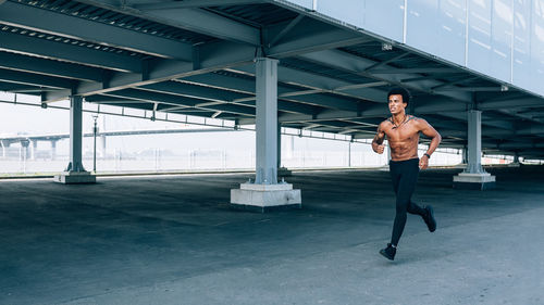 Full length of shirtless man sitting on wall