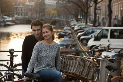 Portrait of smiling friends by bicycle in city