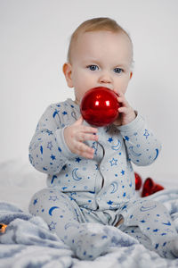 Christmas baby in santa hat, child holding red ball