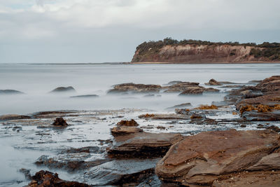 Scenic view of rocks on beach against sky