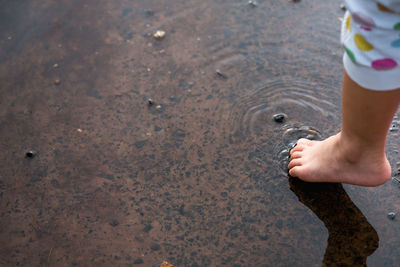 Low section of child standing on sand at beach