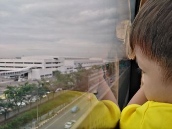 Side view of boy looking through window