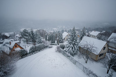 Snow covered trees and buildings against sky