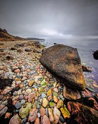 Rocky shore against cloudy sky