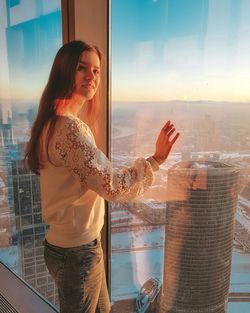 Woman standing by glass window