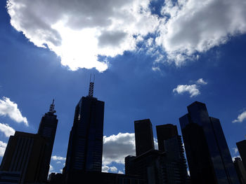 Low angle view of skyscrapers against cloudy sky