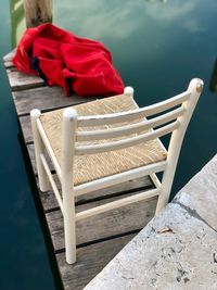 High angle view of empty chair on pier over lake