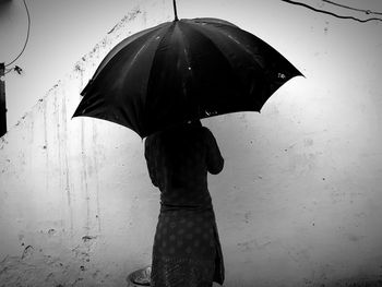 Rear view of woman standing on wet umbrella during monsoon