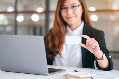 Portrait of businesswoman holding business card in office