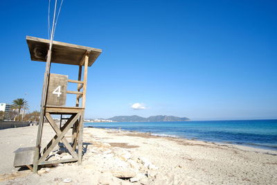 Lifeguard hut on beach against clear blue sky