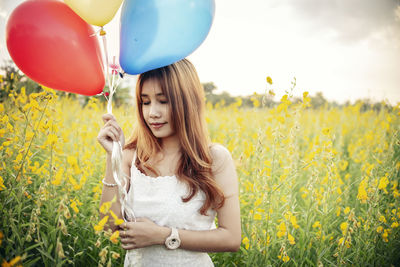 Young woman with yellow flowers in field