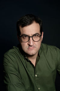 Portrait of man wearing eyeglasses against black background