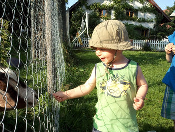 Happy boy standing by fence